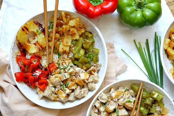 Grilled Chicken and Pineapple Rice Bowls with Teriyaki Glaze in a white bowl with chopsticks. bell peppers and chives garnish on the side of the bowl
