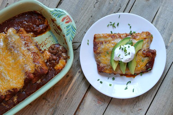 Beef and Cheese Enchiladas on a plate with pan of enchiladas along side