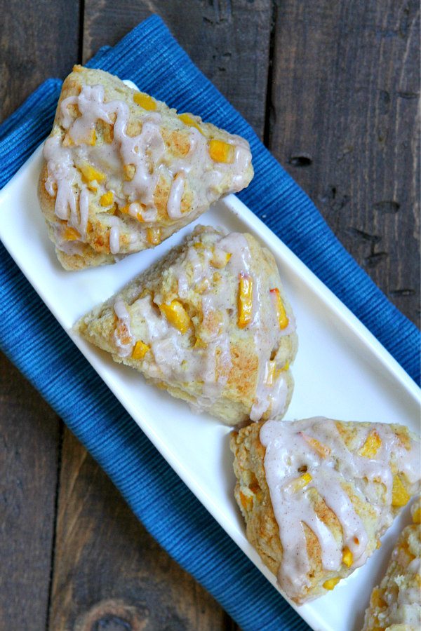 Fresh Peach Scones on a white platter set on a blue napkin on a wood surface