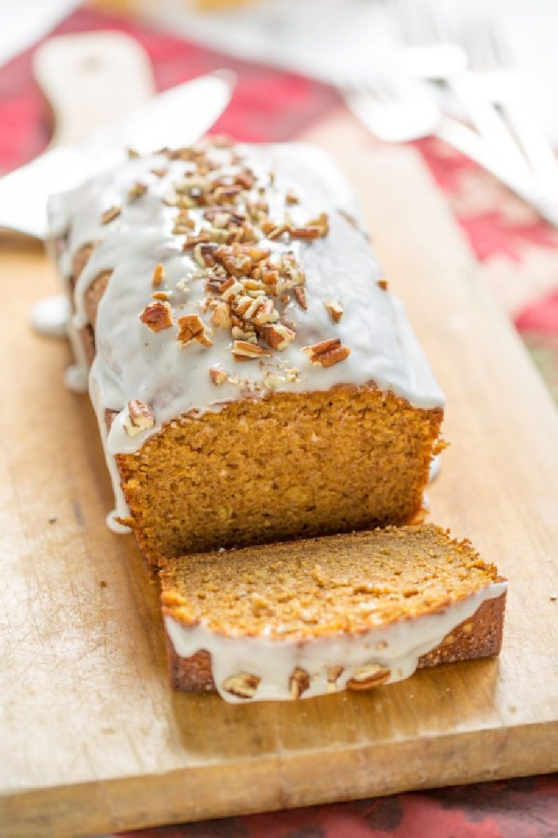 pumpkin loaf cake on cutting board with slice taken out of it