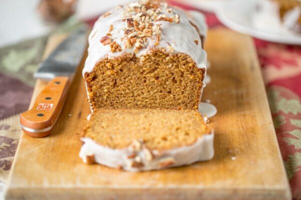 Iced Pumpkin Loaf Cake on a cutting board with slice cut out