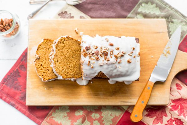 Iced Pumpkin Loaf Cake sliced on a cutting board