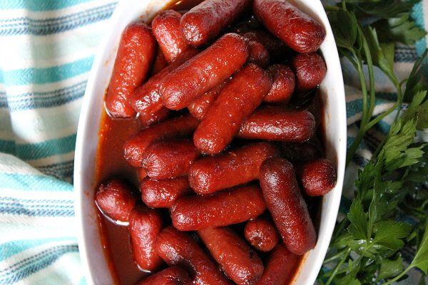 Easy Lil Smokies Appetizer in a white bowl with striped blue towel on one side and fresh parsley on the other