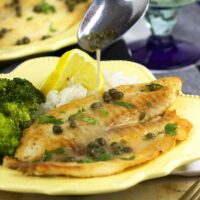 spooning sauce onto plate of tilapia piccata