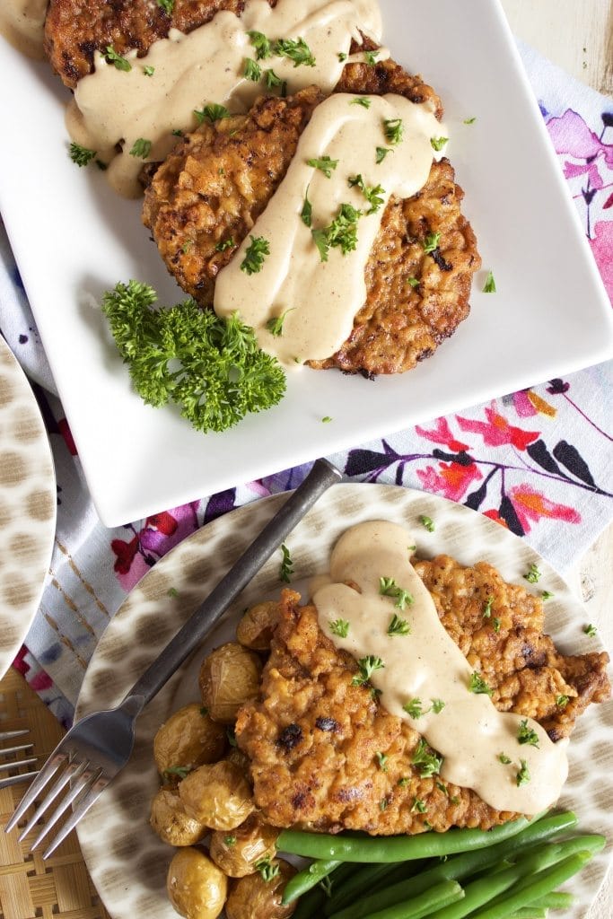 chicken fried steak drizzled with gravy on white plates