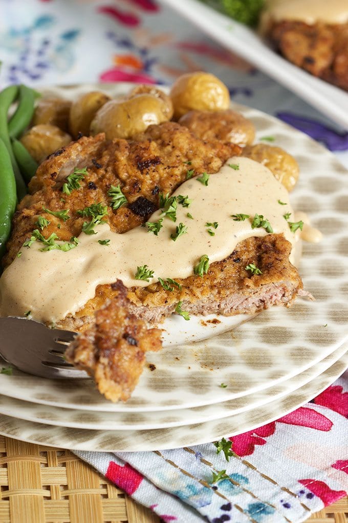 Chicken Fried Steak displayed on a stack of polka dot plates topped with gravy