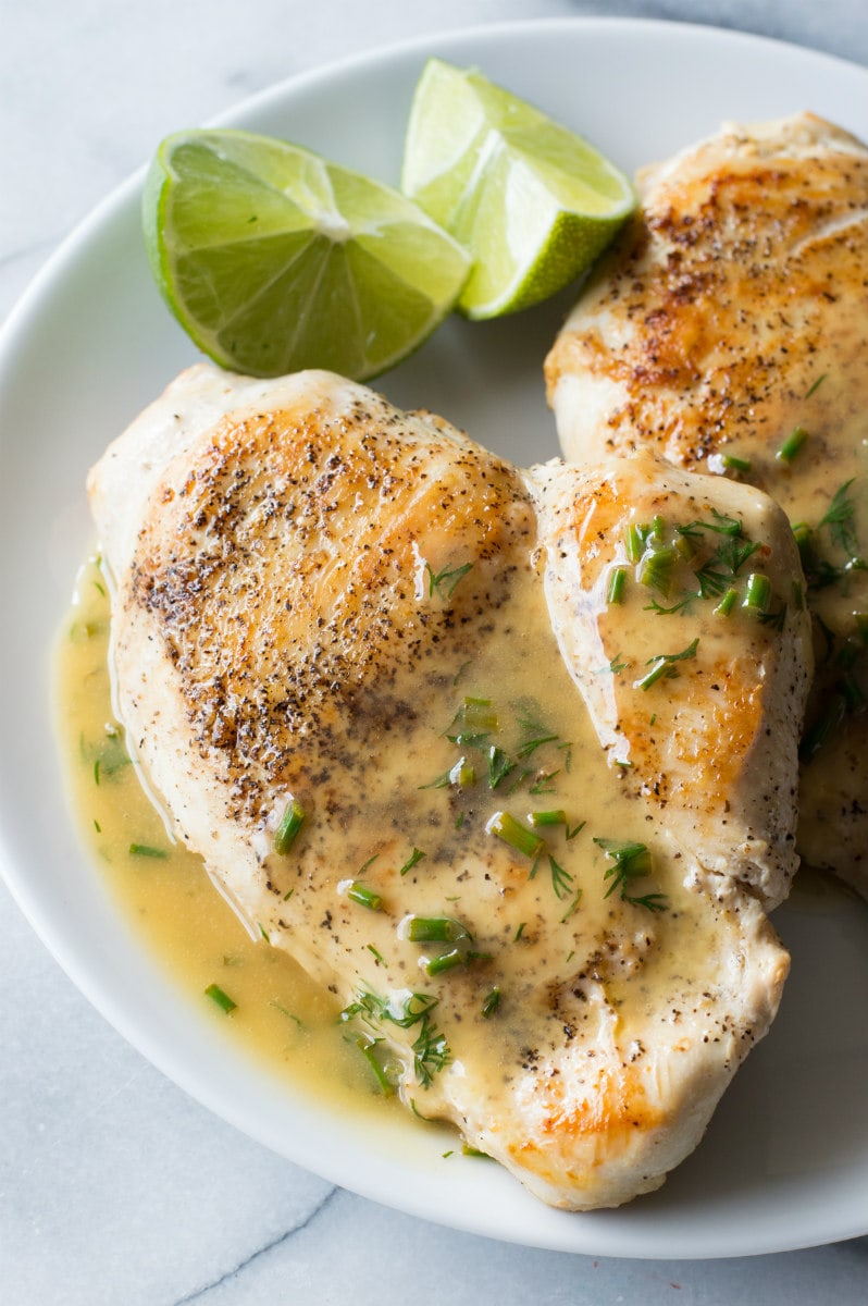 chicken topped with lime butter on a white plate with fresh lime wedges