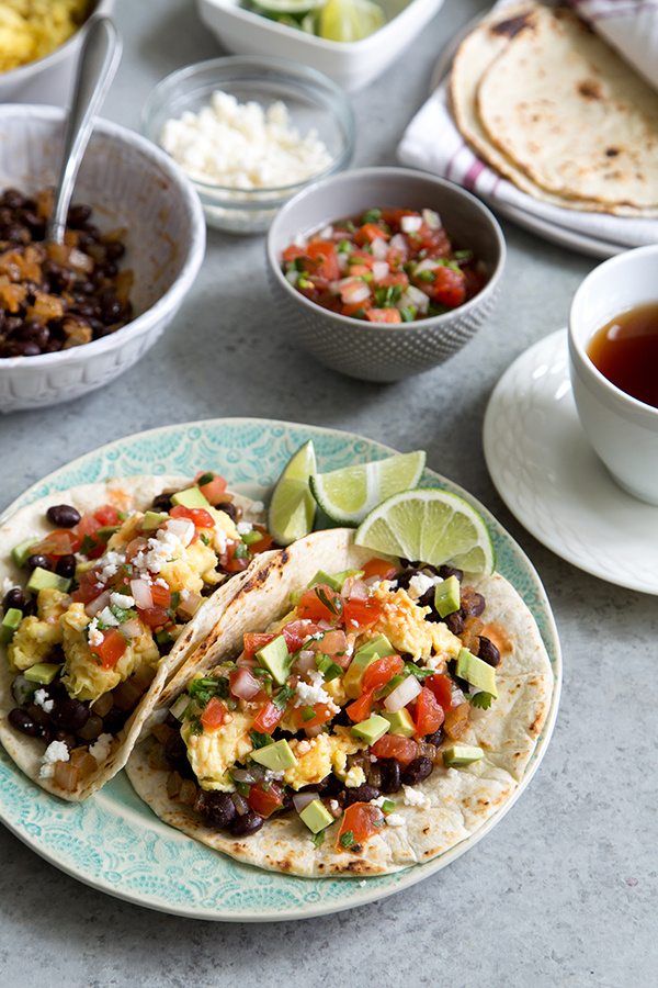 Breakfast Tacos on a plate with toppings in bowls surrounding