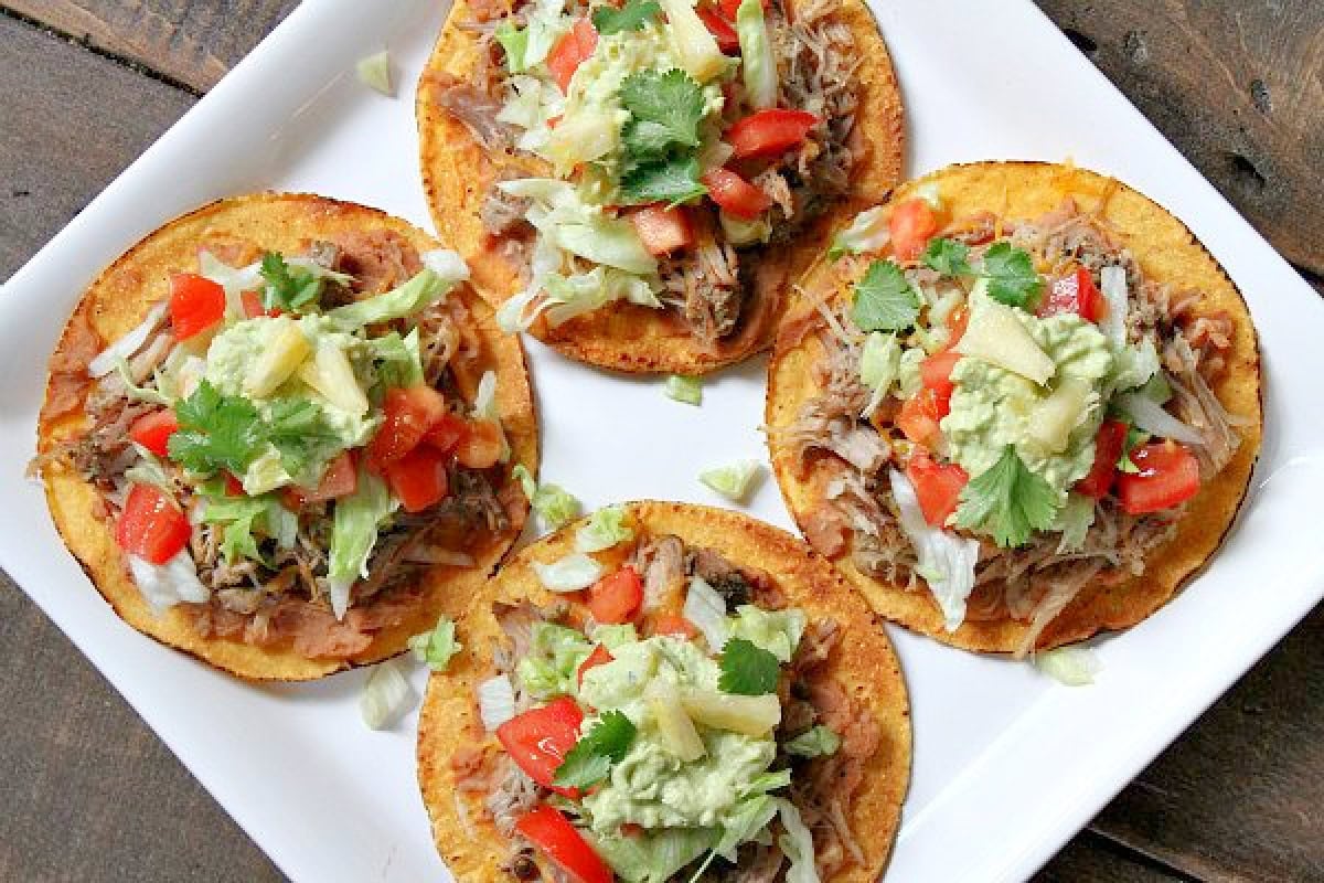 four carnitas tostadas on plate