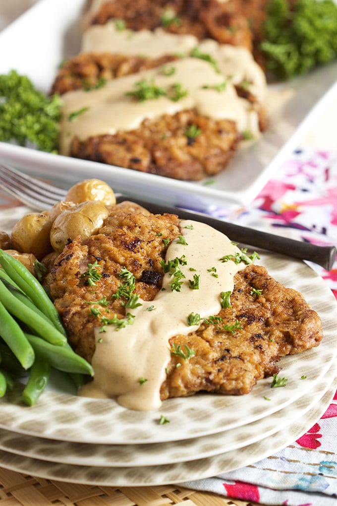 chicken fried steak with gravy on top and fresh green beans. Displayed on a polka dot stack of plates.