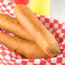 three Corn Dogs in a basket lined with red/white checked paper with ketchup and mustard bottles and dishes with mustard in it on the side
