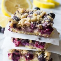stack of blueberry lemon crumb bars with fresh cut lemons in background