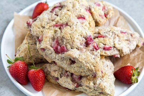 Stack of strawberry Buttermilk Scones on a white plate with fresh strawberries