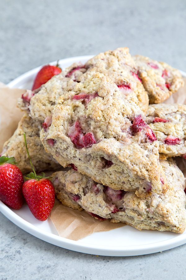 stack of Strawberry Buttermilk Scones on a white plate with fresh strawberries