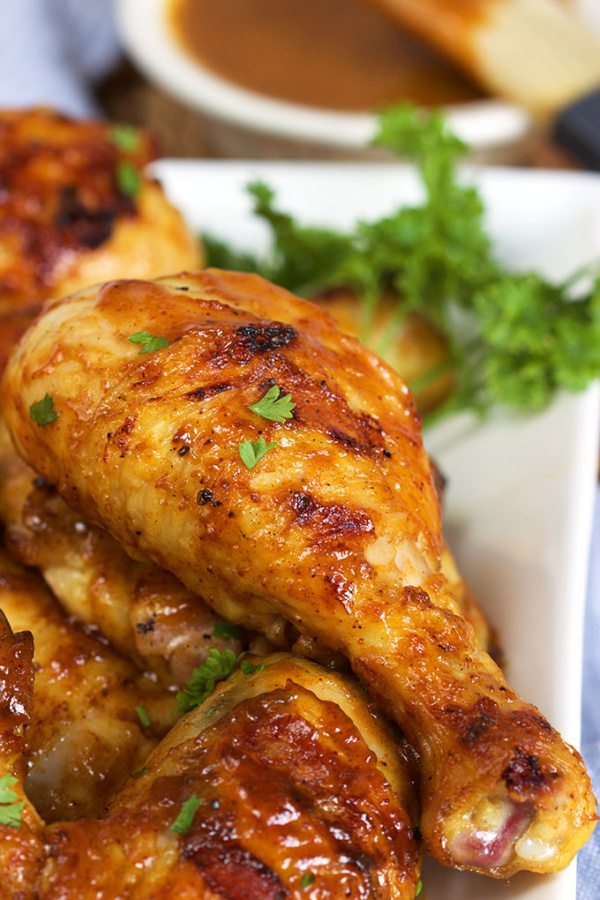 Carolina Style Barbecue Chicken on a white platter garnished with parsley. bowl of sauce in the background