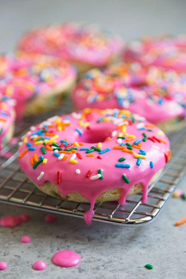 Baked Birthday Cake Doughnuts with pink glaze on a cooling rack