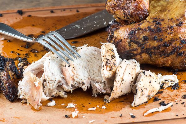 Beer Can Chicken cut up with a fork on a cutting board