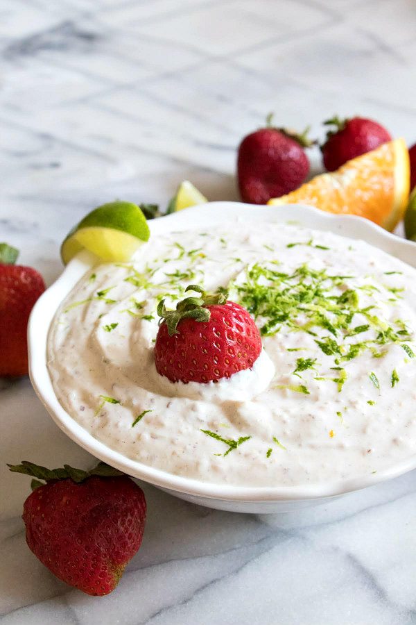 margarita fruit dip garnished with strawberries and lime, displayed in a white bowl on a marble surface