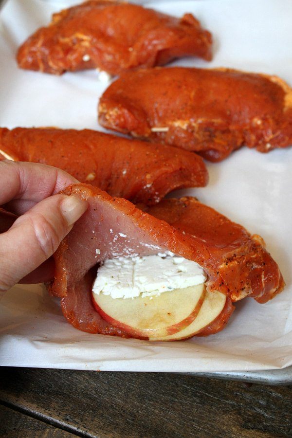 Stuffing Pork Chops with apple and blue cheese on a white platter