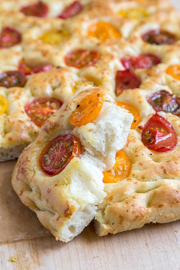 Tomato Focaccia Bread on a cutting board with one slice leaning up against the rest of the bread