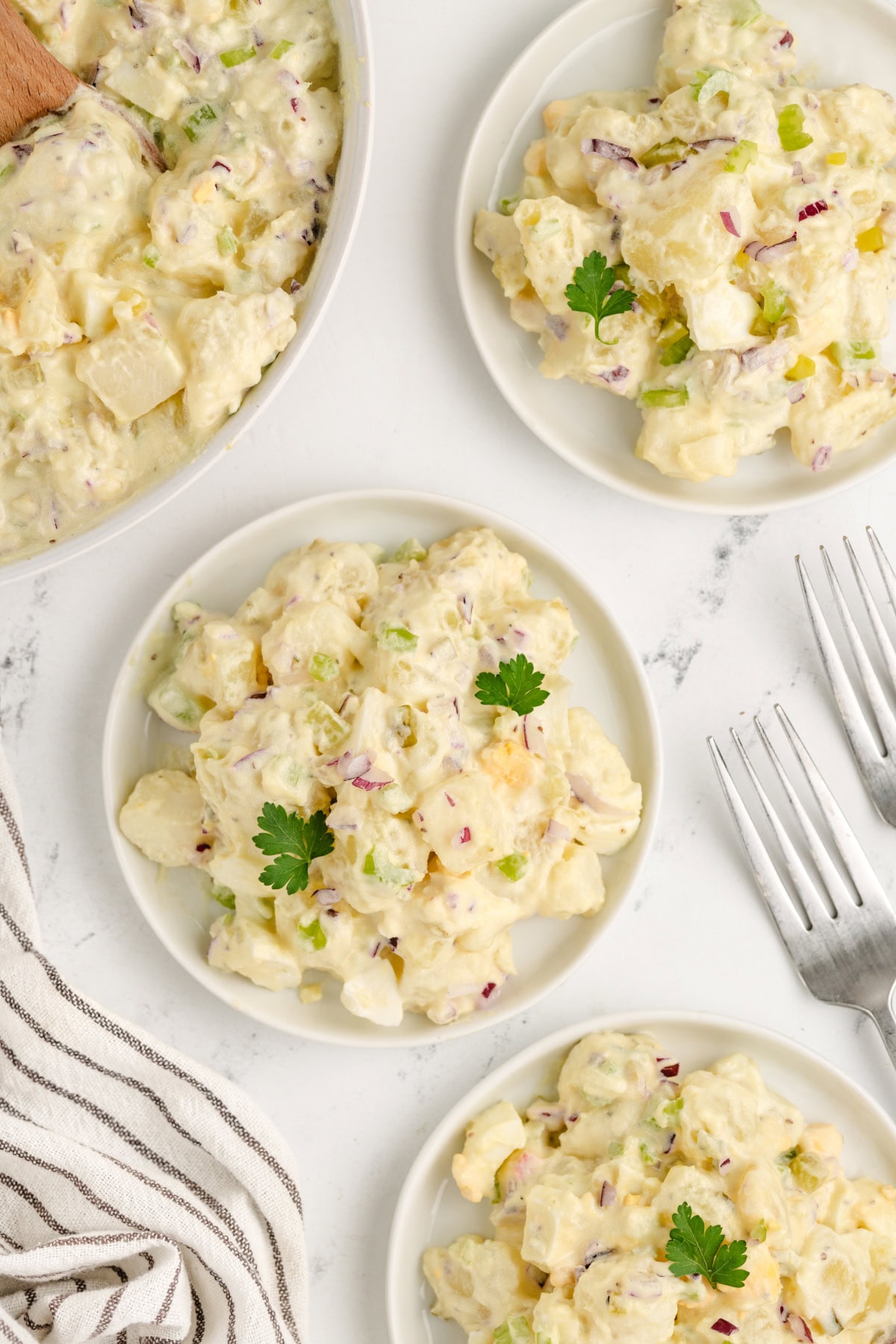 The perfect potato salad for every barbecue! American Potato Salad recipe from RecipeGirl.com several servings of american potato salad on plates