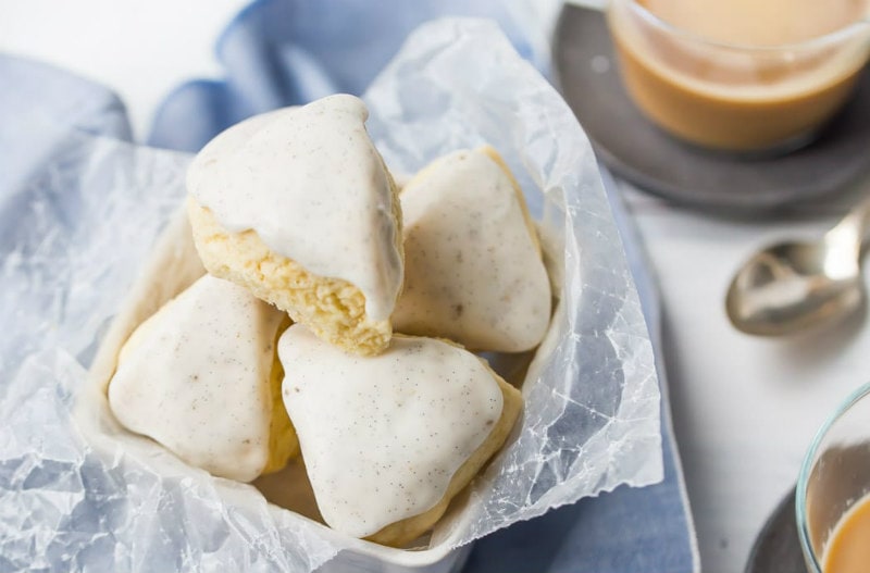 vanilla bean scones spilling out of a display basket with coffee and spoon in the background- on top of a blue napkin