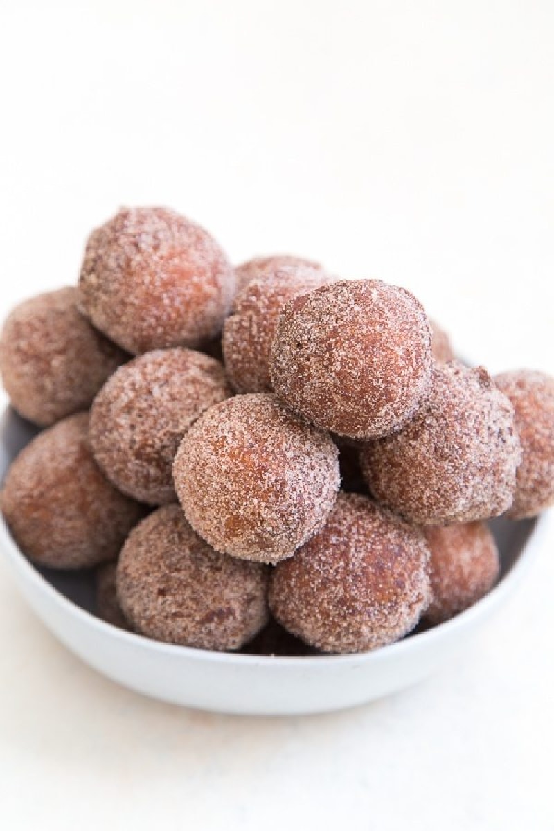 apple cider doughnut holes stacked in a white bowl