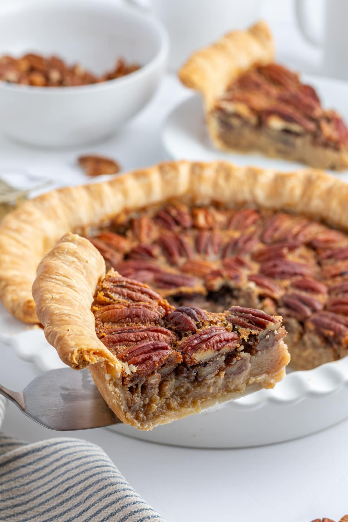 spatula taking out slice of pecan pie out of whole pie