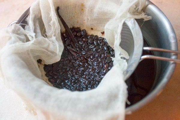 Making Homemade Kahlua draining the beans through cheesecloth