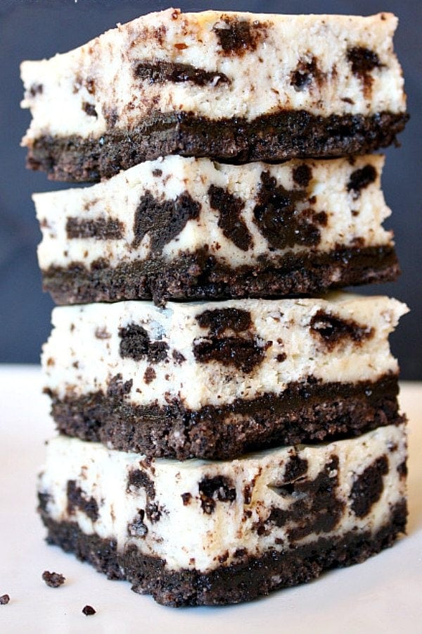 four pieces of cookies and cream cheesecake bars stacked on top of each other