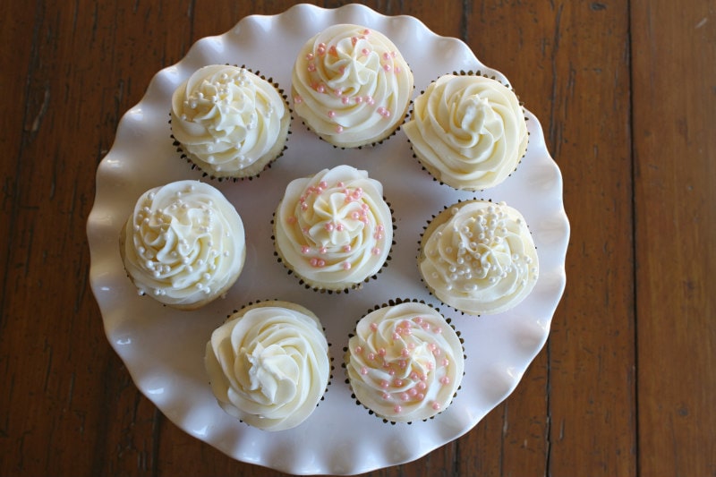 overhead shot of white frosted cupcakes on a white cake platter