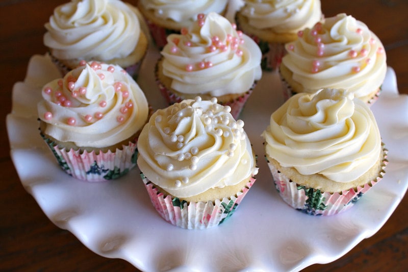 wedding cupcakes with white frosting displayed on a white cake platter