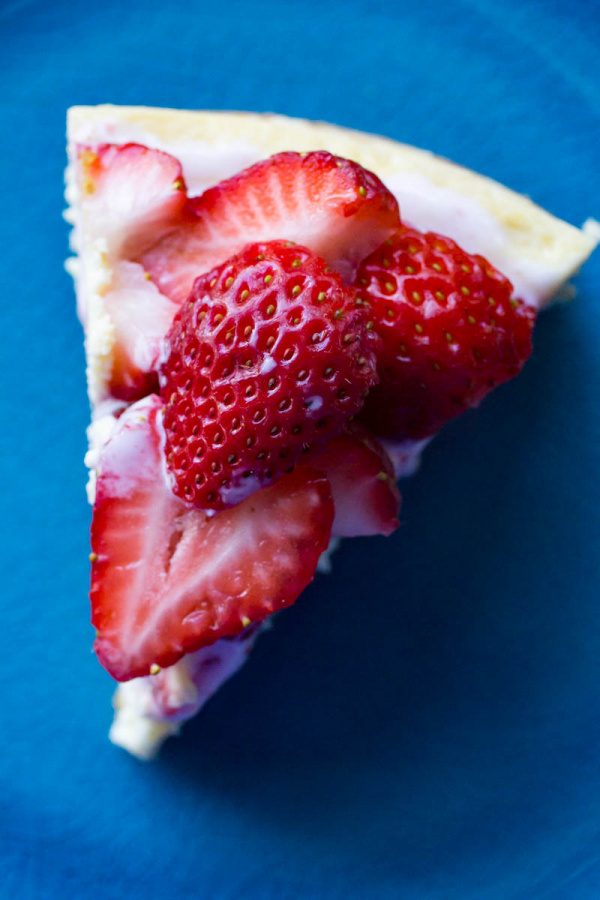 Instant Pot Cheesecake on a blue plate with fresh strawberries on top
