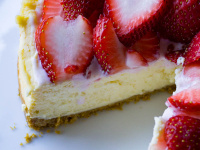 Instant Pot Cheesecake with piece cut out and strawberries on top on white plate
