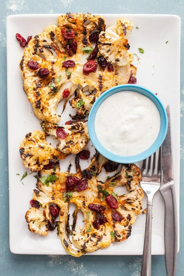 grilled cauliflower steaks with yogurt sauce on a platter