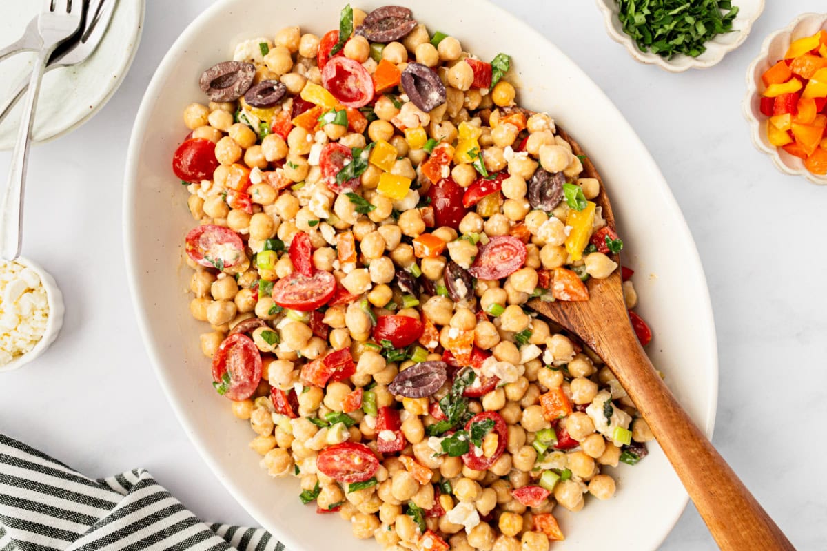 This Mediterranean Chickpea Salad is a super popular, delicious and easy salad recipe from RecipeGirl.com. mediterranean chickpea salad in a bowl with wooden spoon