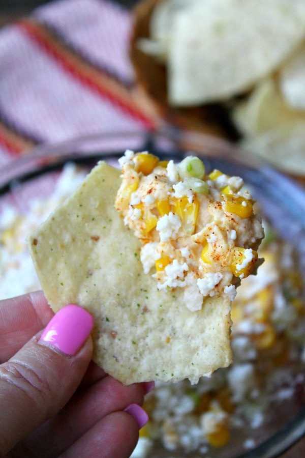 Slow Cooker Mexican Street Corn Dip recipe from RecipeGirl.com : Elote Dip : Corn Dip : Crockpot Mexican Street Corn Dip Mexican Street Corn Dip on a chip - fingers holding have pink fingernails