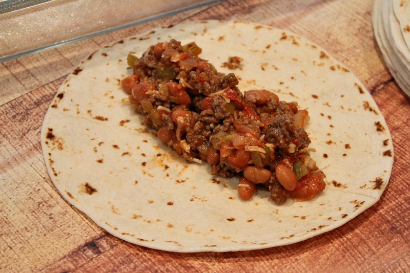 a tortilla with beef and bean filling on top of it