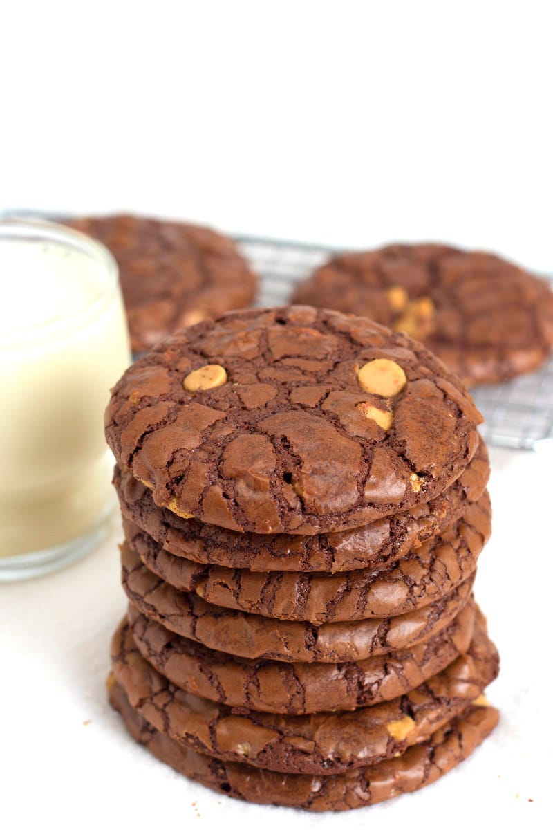 stack of Chocolate Wows Cookies with a glass of milk and a rack of more cookies in the background