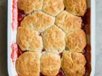 overhead shot of strawberry rhubarb cobbler in a white casserole dish