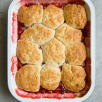 overhead shot of strawberry rhubarb cobbler in a white casserole dish
