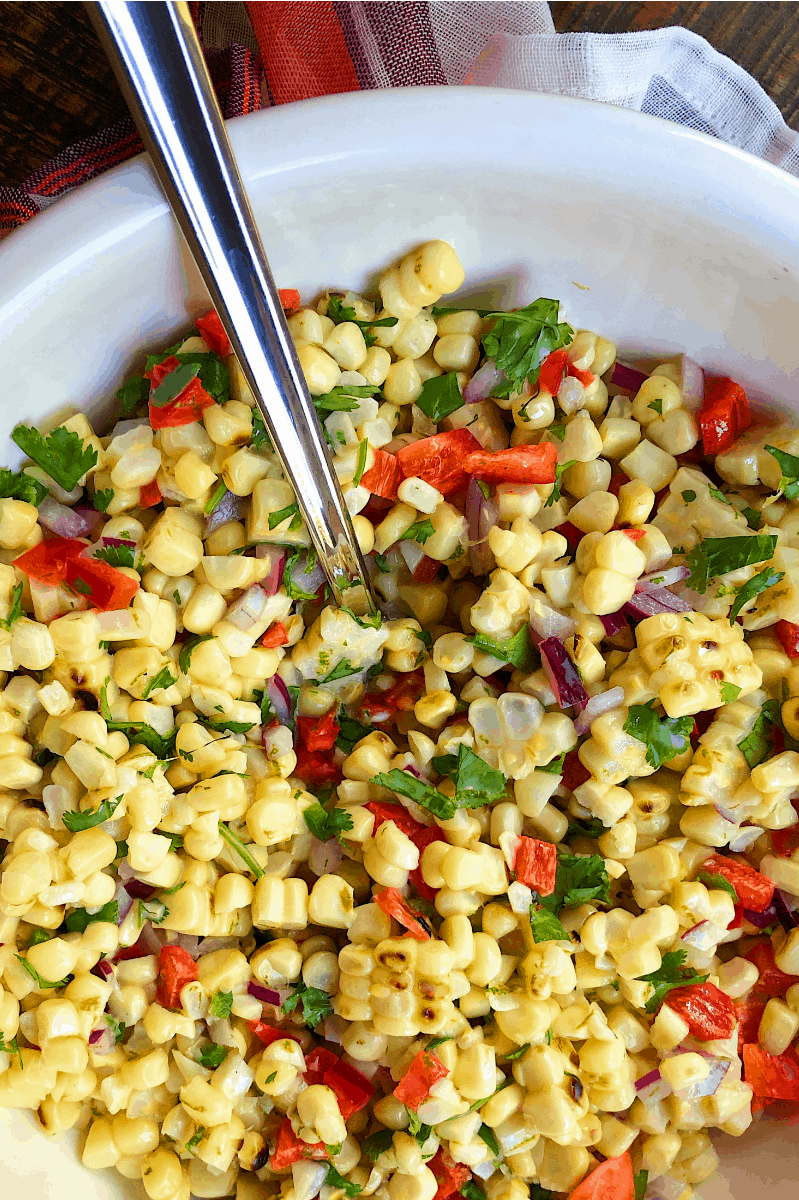 Grilled Corn Salad in a white bowl with a serving spoon