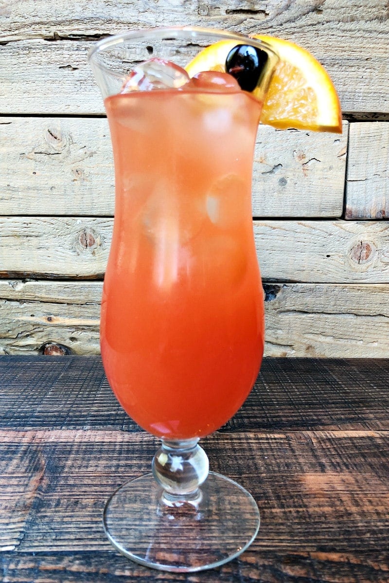 hurricane cocktail in a hurricane glass with a wooden background