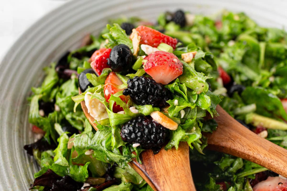 serving spoons in triple berry salad