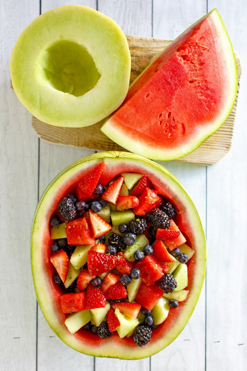 overhead shot of watermelon fruit bowl and melon and watermelon sitting on a wood board 