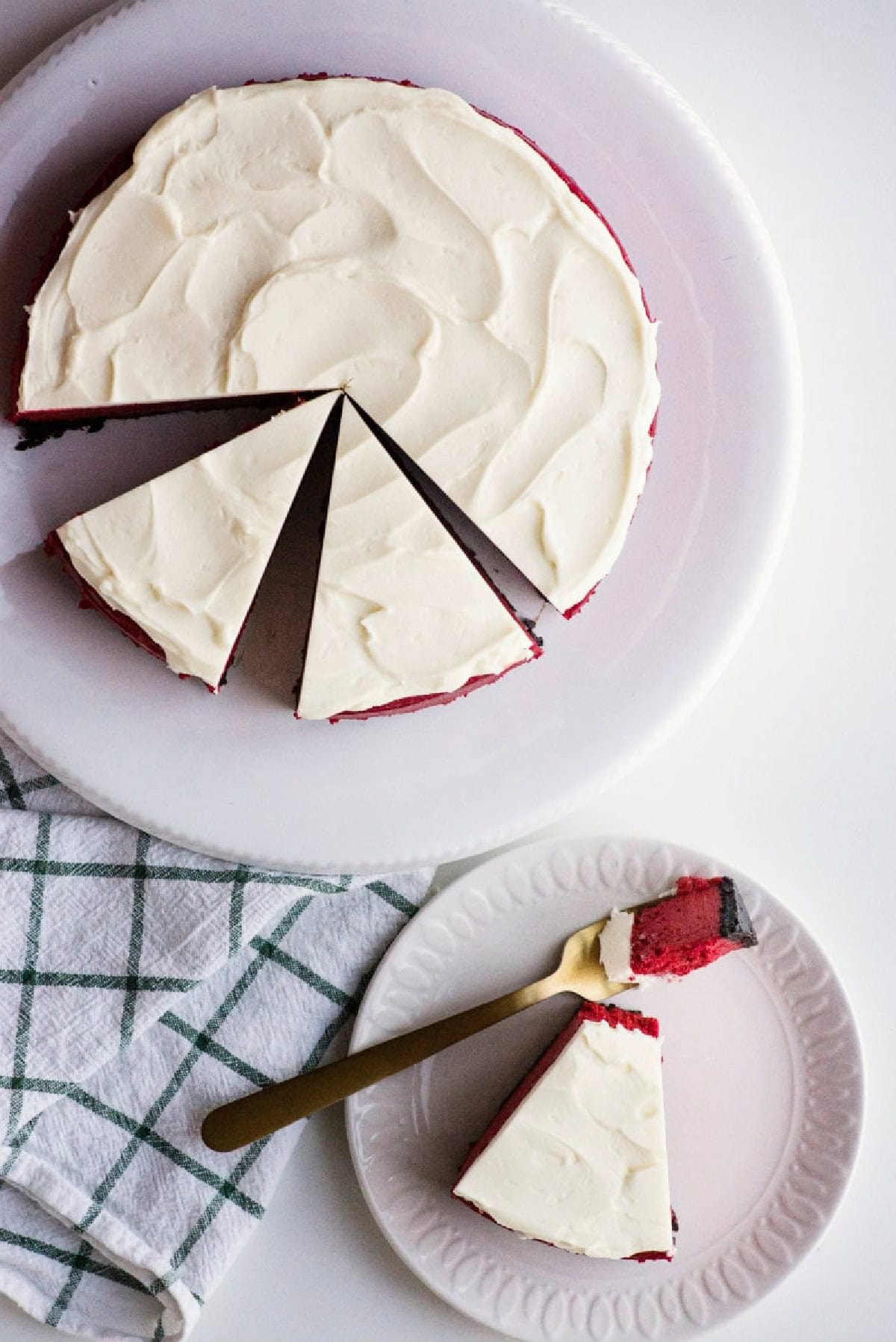 This gorgeous Red Velvet Cheesecake has a creamy red velvet filling, chocolate Oreo crust and rich cream cheese frosting. It's an impressive make-ahead dessert for Christmas, Valentine's Day, holidays and special occasions. overhead shot red velvet cheesecake cut into slices