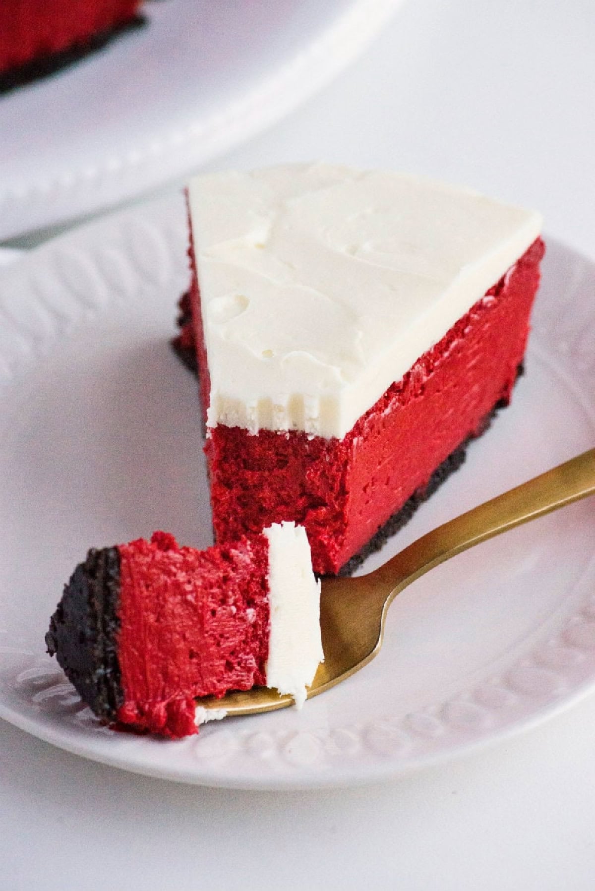 This gorgeous Red Velvet Cheesecake has a creamy red velvet filling, chocolate Oreo crust and rich cream cheese frosting. It's an impressive make-ahead dessert for Christmas, Valentine's Day, holidays and special occasions. red velvet cheesecake with bite taken out of it