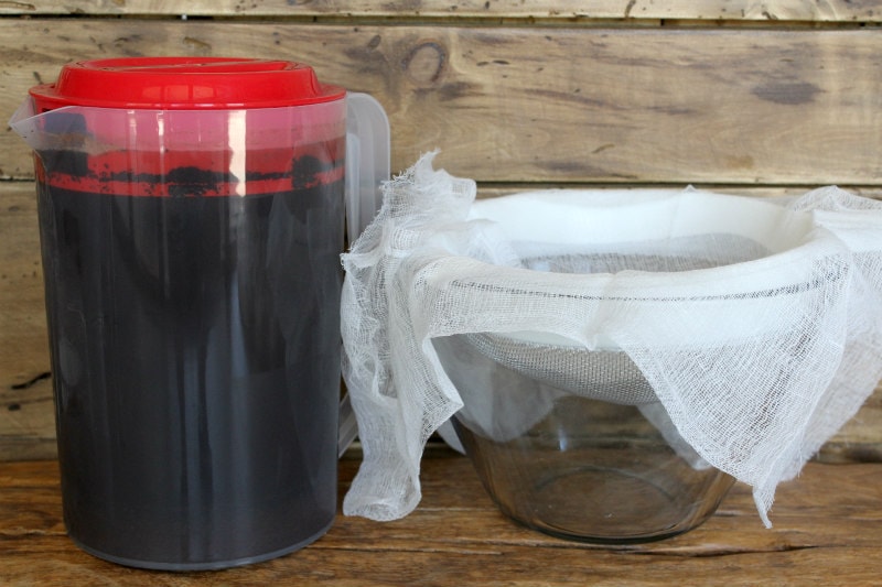 pitcher of cold brew coffee sitting next to glass bowl lined with cheesecloth