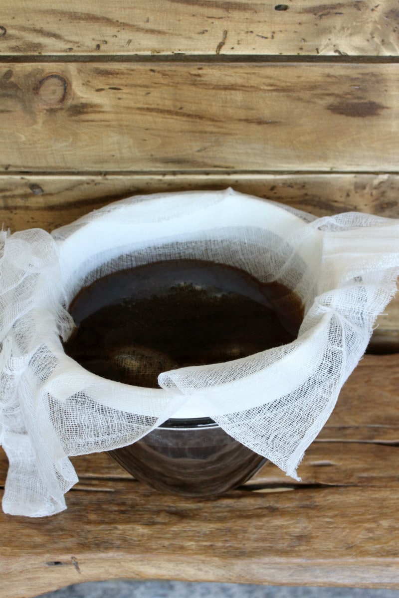 straining coffee and grounds through cheesecloth into a bowl