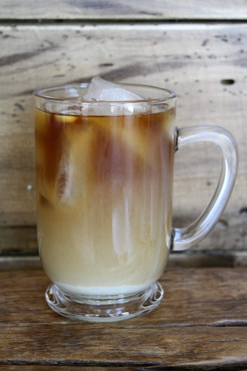 glass mug of cold brew coffee with cream with a wood backdrop